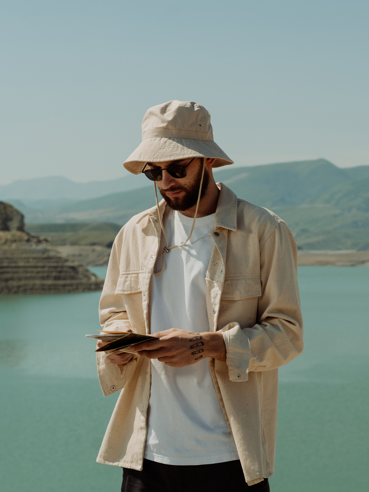Men with tan bucket hat with string wearing map for hicking